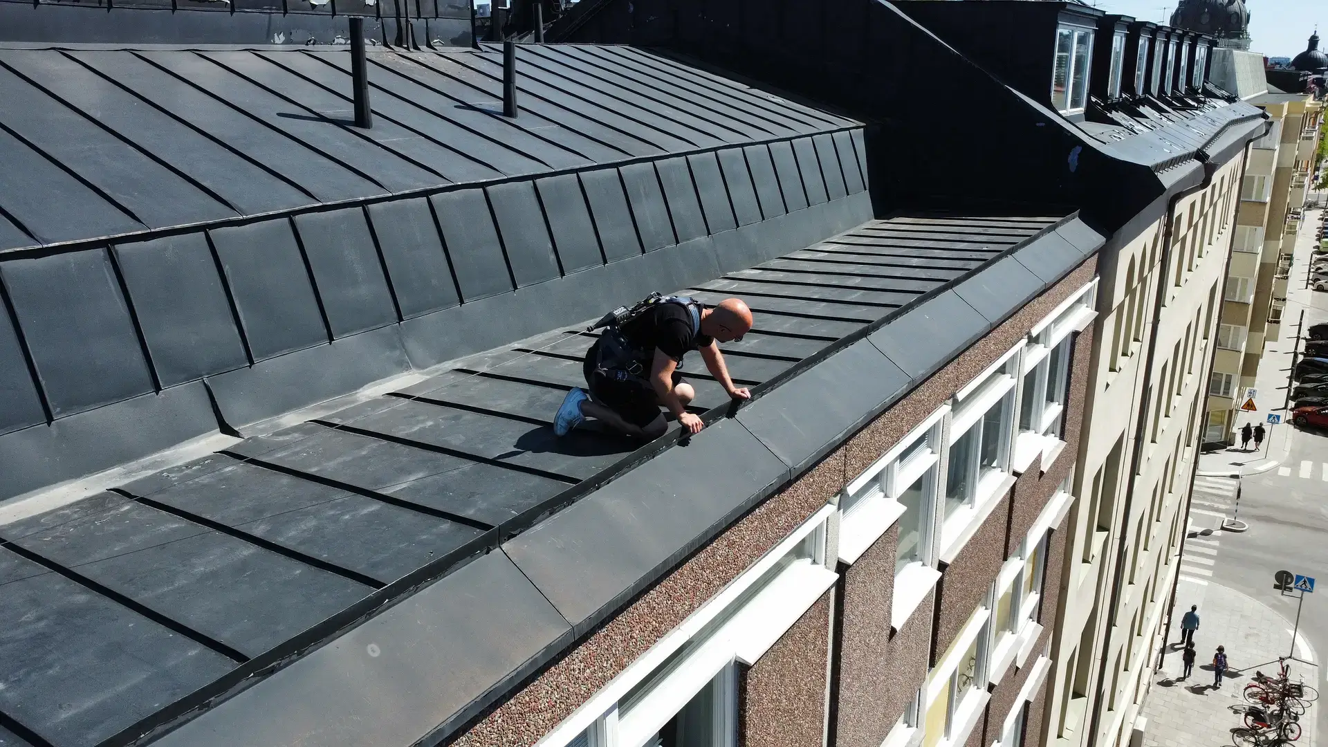 En person kryper på kanten av ett högt stadsbyggnads tak.